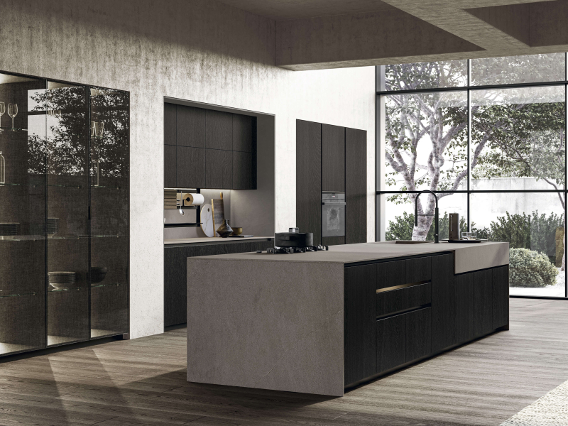 Напольные и высокие тумбы из карбонового дуба с черным изогнутым пазом. Задние и боковые панели, а также столешница из керамогранита Moka Abujardado Jasper. Высокие тумбы Vidro с черной алюминиевой рамой и дымчатым стеклом с эффектом ткани.