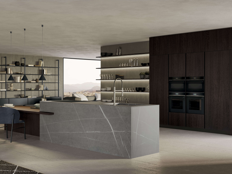 Островные тумбы бежевого цвета «Феникс» с изогнутым пазом. Столешница, боковые и задние панели острова из керамогранита Gris Natural Senda. Столешница и полки из термообработанной дубовой древесины. Высокие тумбы из термообработанной дубовой древесины с и