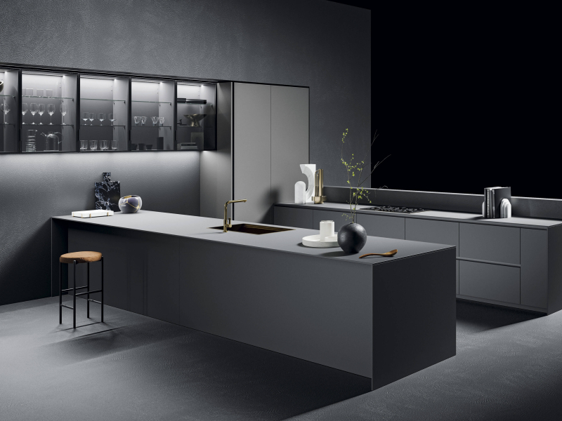 Нижние модули и столешница Fenix nero ingo с изогнутым бортиком. Верхние модули из оксидированной нержавеющей стали, покрытой лаком. Настенные модули Vidro с матовой лакированной структурой nero и дымчатым стеклом.